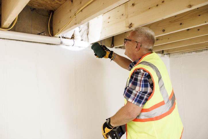 A man inspecting a home wearing protective gear.