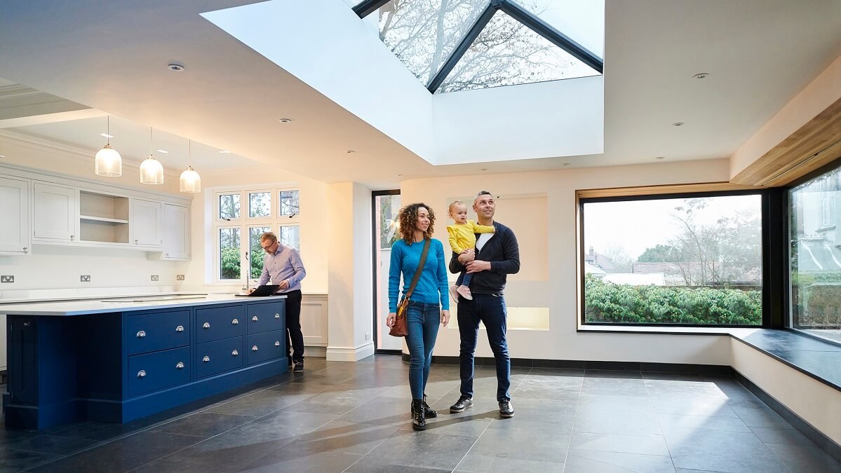 Family admires the interior of a home for sale while their real estate agent prepares documents.