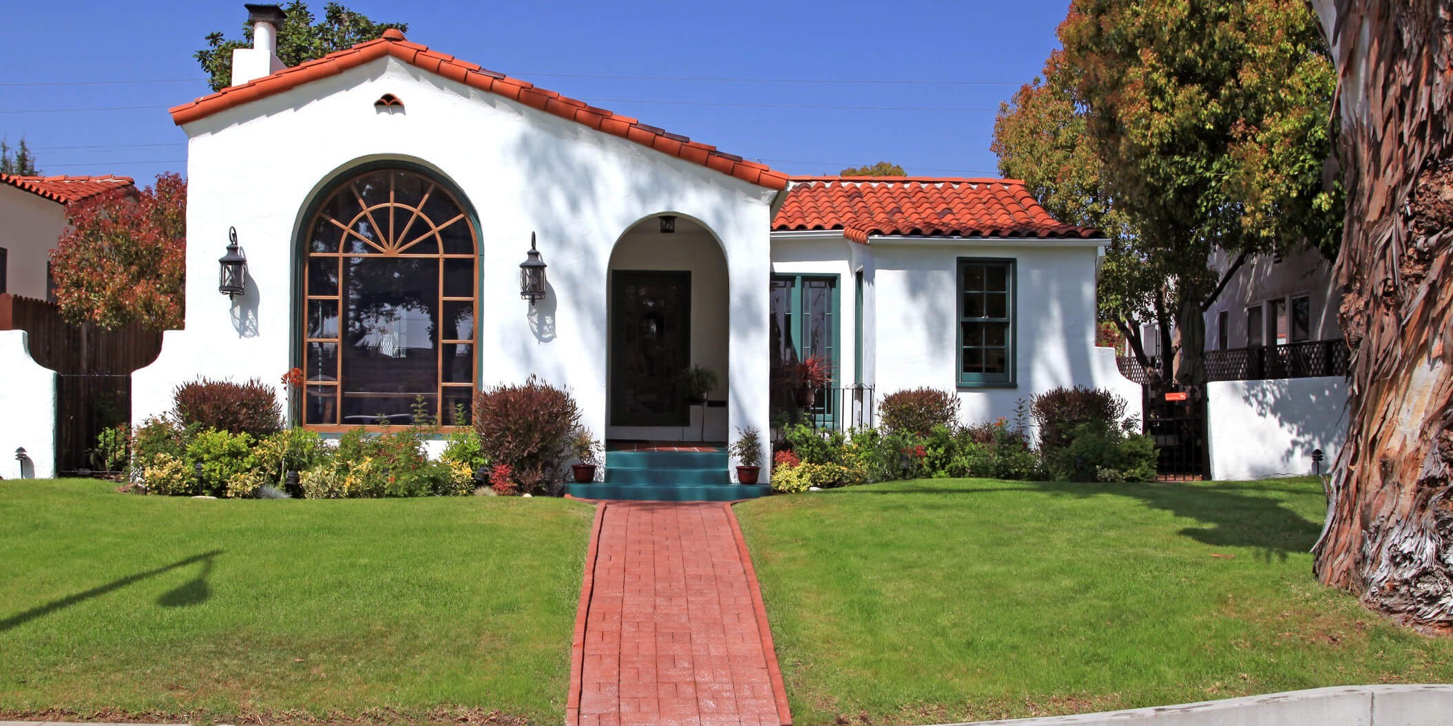 Front view of a Spanish style home with a clay tile roof and white walls.