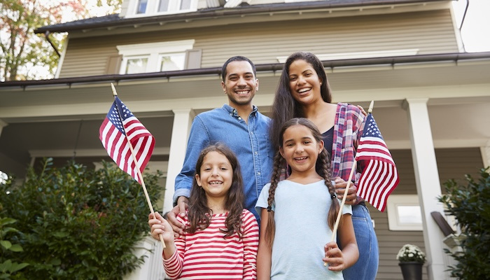 Family holding American flags outside of home.