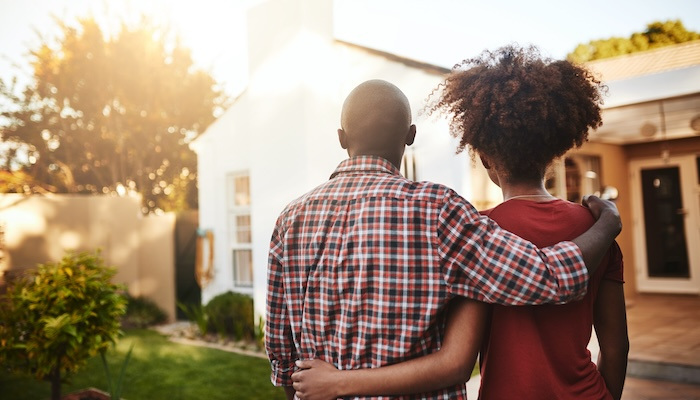 Rear view of a man and woman viewing a house.